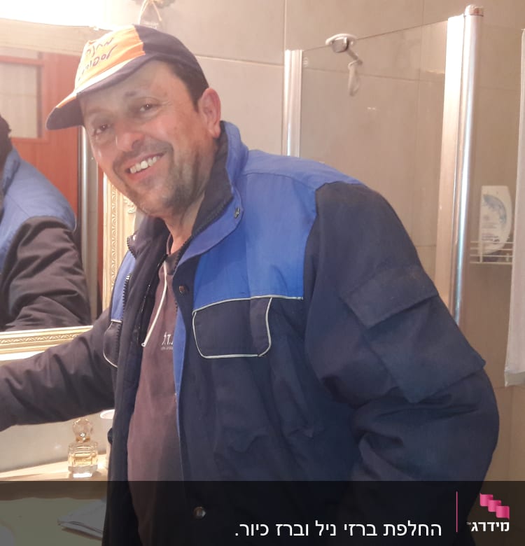 אדם עם כובע מתקין ברז בחדר אמבטיה